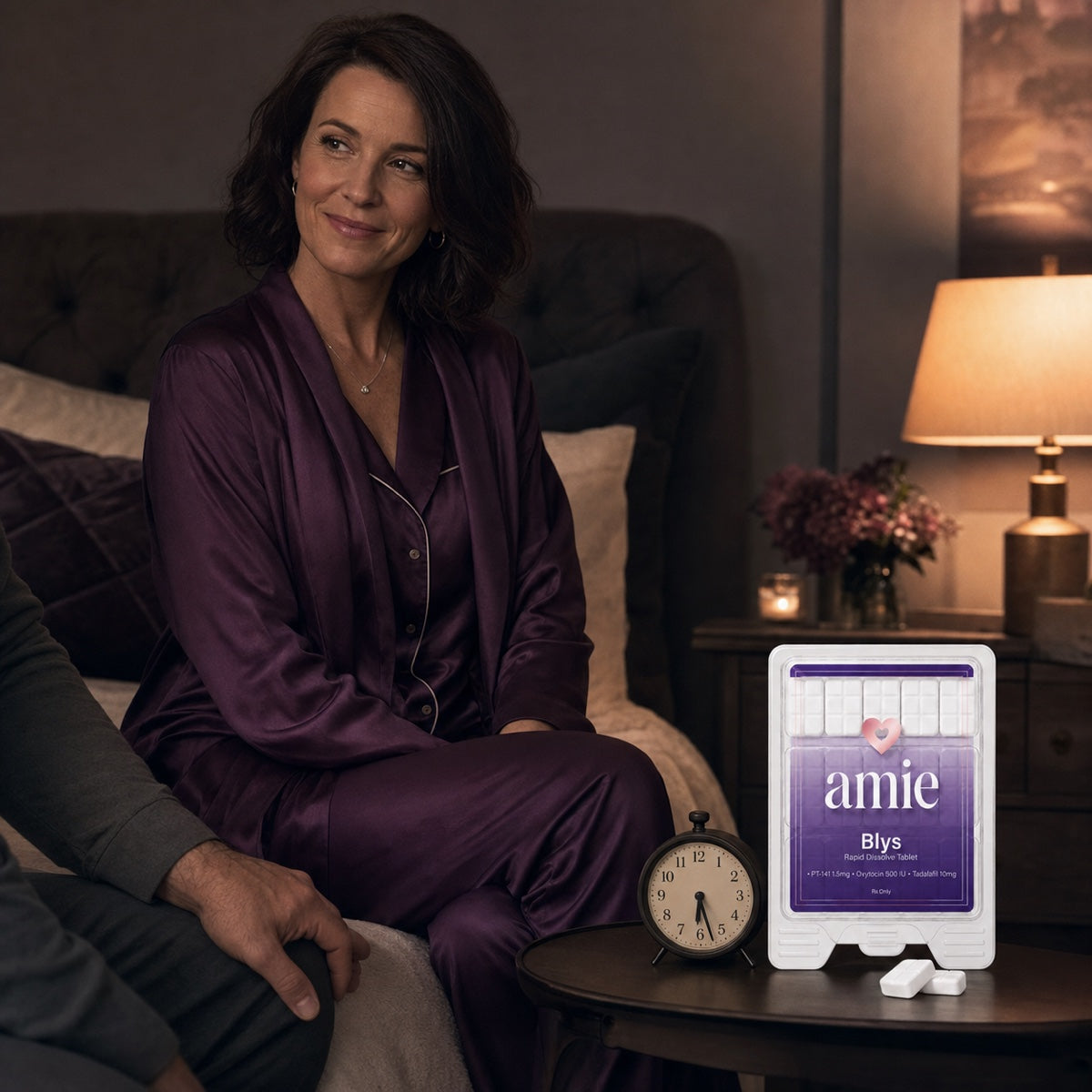 Woman in an evening bedroom beside Blys by Amie and a bedside clock