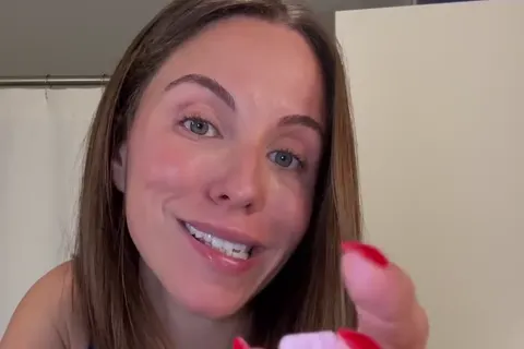 A smiling woman holding up a pink Blys rapid-dissolve tablet